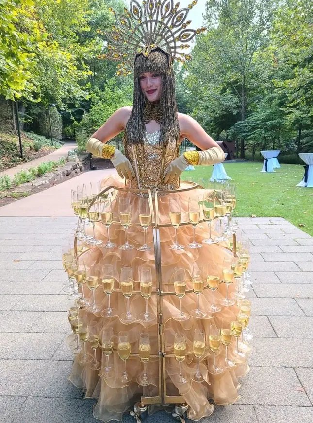 A greeter in a champagne-glass skirt welcoming gala guests
