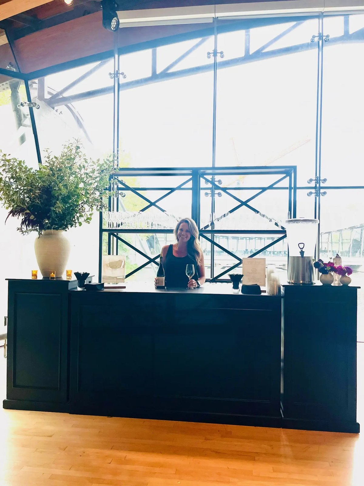 A bartender at a black bar inside a glass-walled corporate atrium