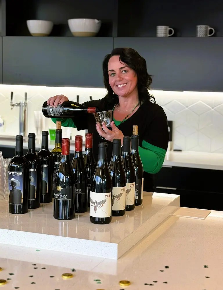 A Tie 1 On bartender pouring wine behind a lineup of bottles