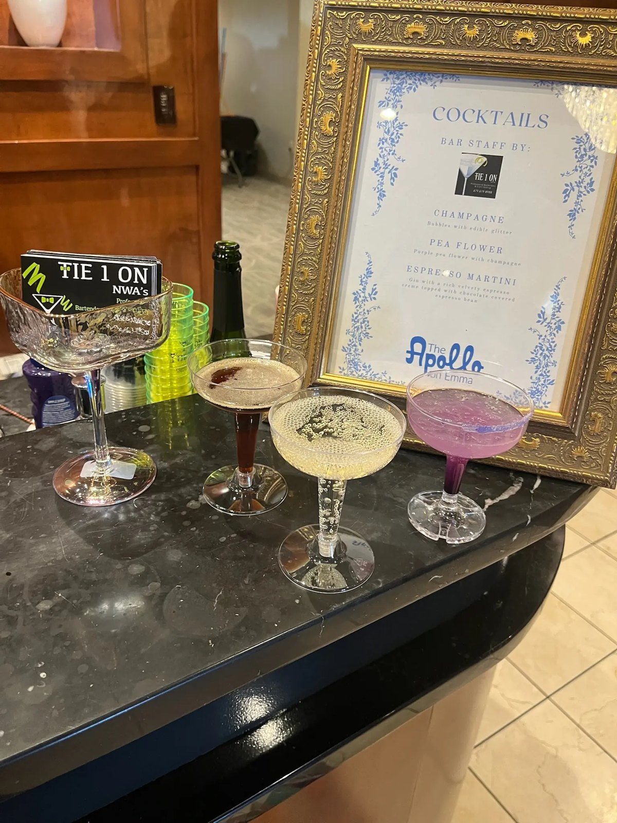 Three signature cocktails beside a printed Tie 1 On menu card