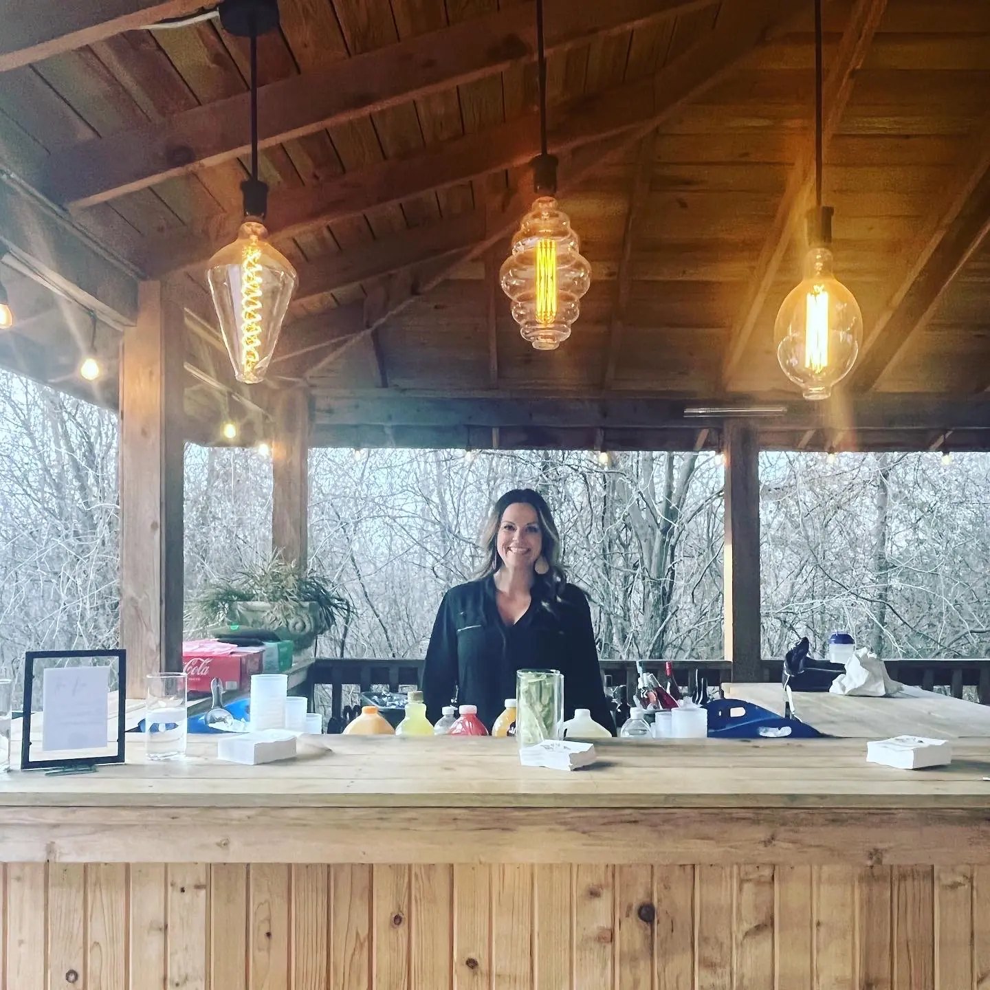 A bartender under a pavilion lit by Edison bulbs