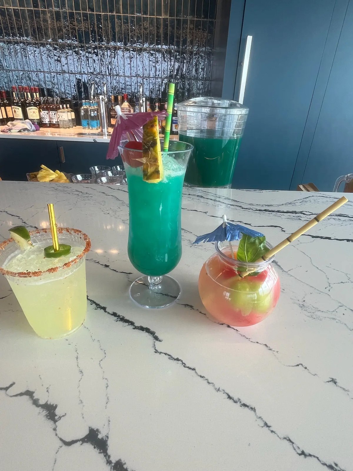 Three colorful signature cocktails on marble